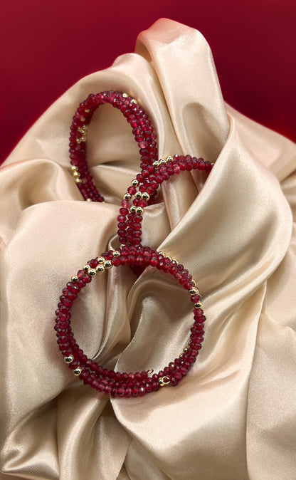 Red beaded bracelet with gold accents on beige fabric. AGATE stone
