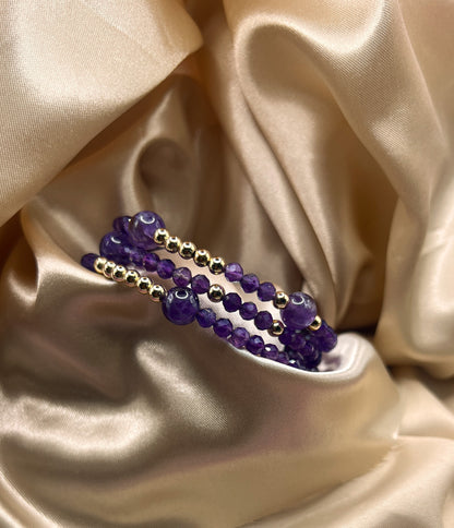 Purple beaded bracelet with gold accents on a beige satin background. Amethyst Stone.