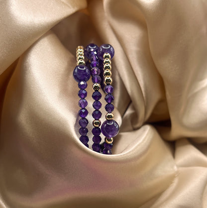 Purple beaded bracelet with gold accents on a beige satin background. Amethyst Stone.