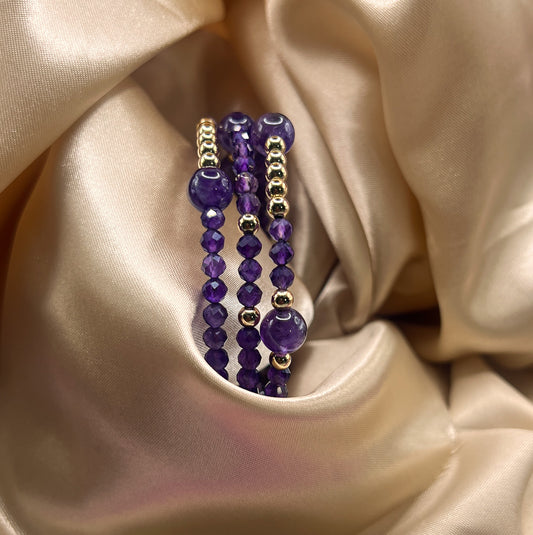 Purple beaded bracelet with gold accents on a beige satin background. Amethyst Stone.